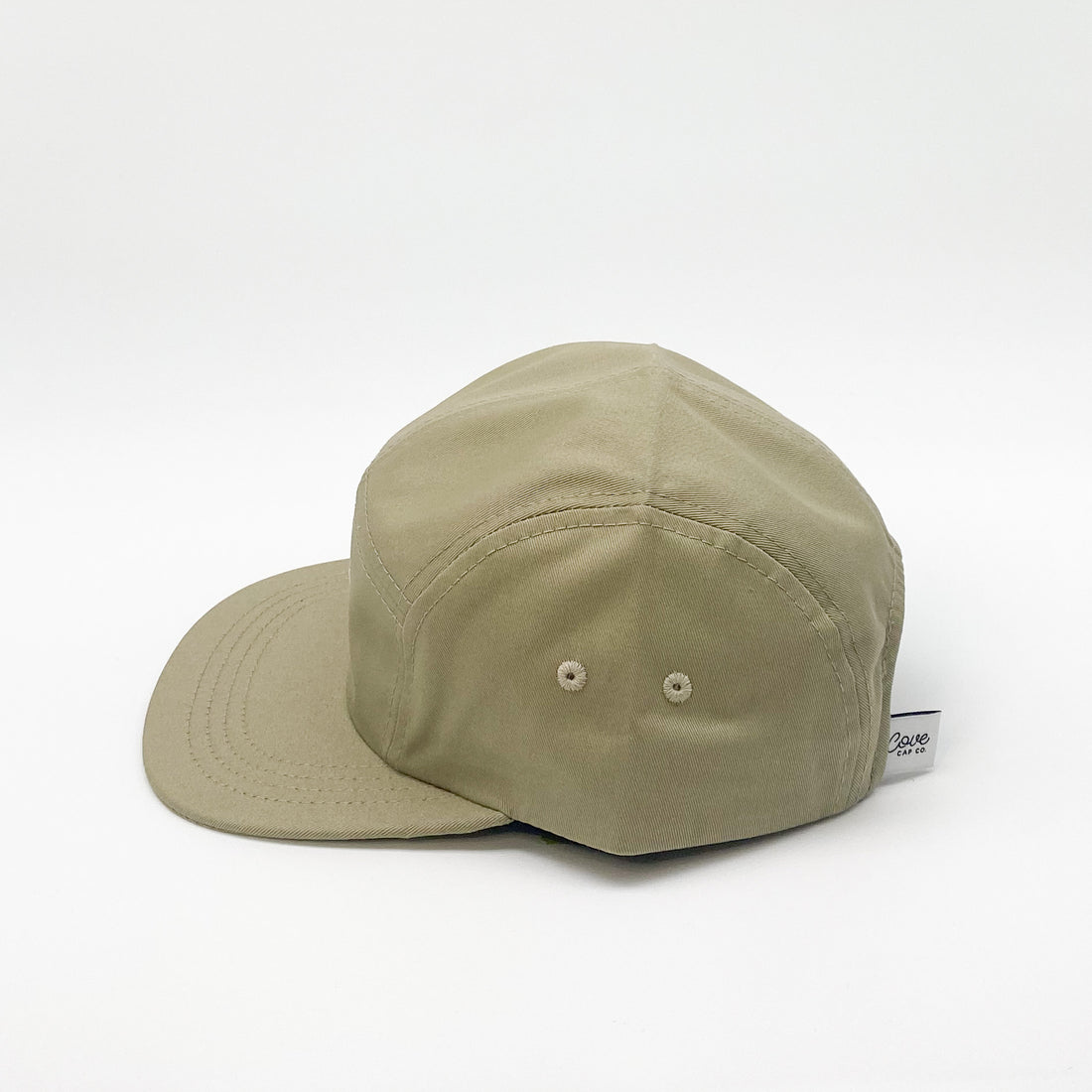 Side profile of a khaki green adult hat. Minimalist five-panel design, made in Canada out of organic cotton. Hat has an adjustable soft velcro closure and two eyelets on each side. 